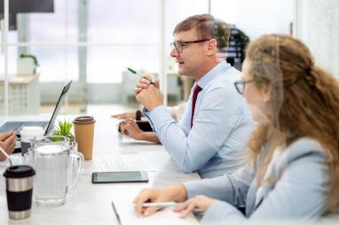 Table of business people, zeroed in on one man speaking