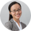 Susie Duong wears a gray suit jacket and glasses and is smiling at the camera