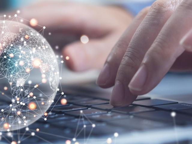 Person typing on computer, global image overlay