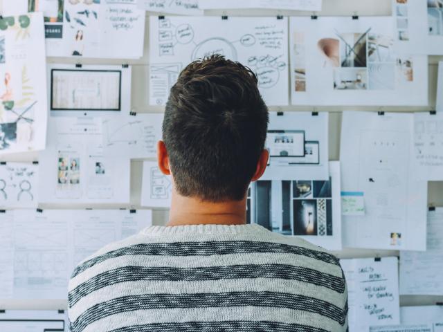 Man staring at wall of complicated papers