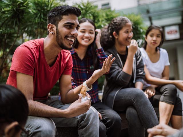 Group of students chatting and eating lucnh together outside
