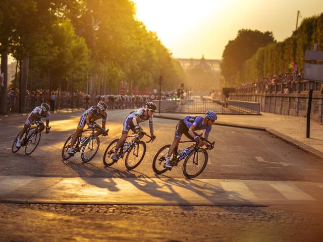 Cyclists racing at sunset down a paved street