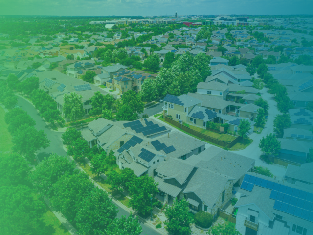 A blue and green gradient filter over a drone shot image of a green neighborhood.