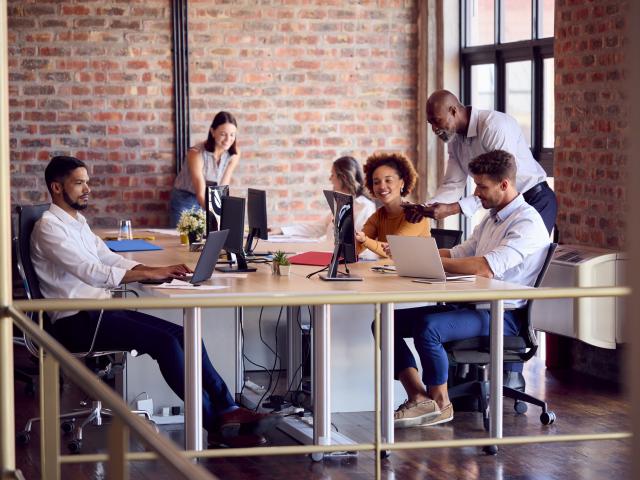 Colleagues talking around a desk in an open office space