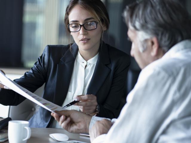 A woman shoes a man something on a piece of paper