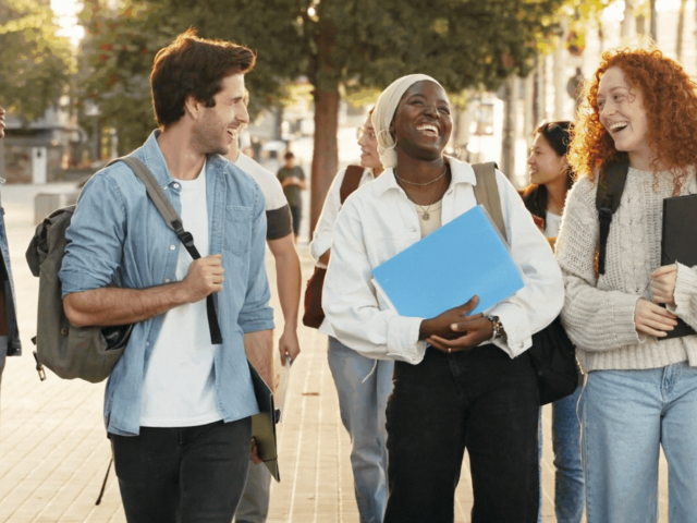 A group of students outside smiling and talking to each other