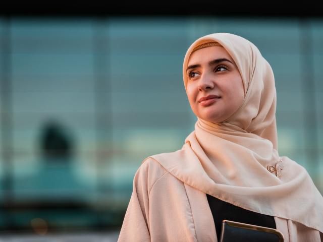 A woman in a cream headscarf looking to the left