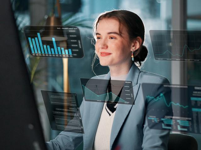 A young woman smiles as she sits at a computer