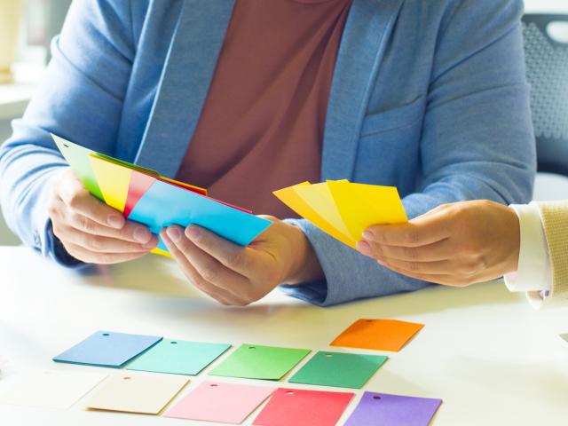 Two professionals consult their notes while sorting colorful index cards into groups