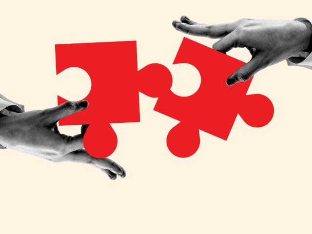 Hands connecting red puzzle pieces on a tan background