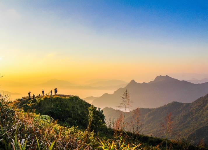 Group of people standing on a hilltop at sunset