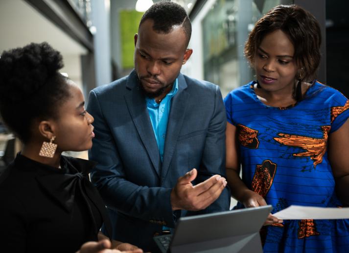 Three people standing looking at a computer