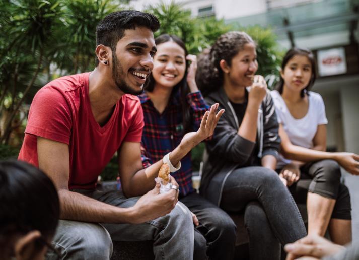 Group of students chatting and eating lucnh together outside