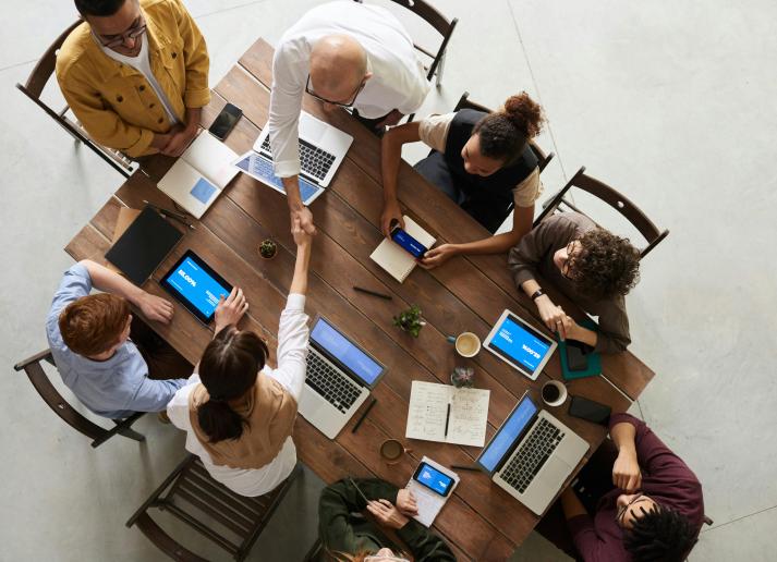 A group of people sitting at a table with laptops in front of them, bird's eye view