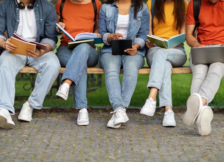 Jeans clad legs of college students sitting on a bench