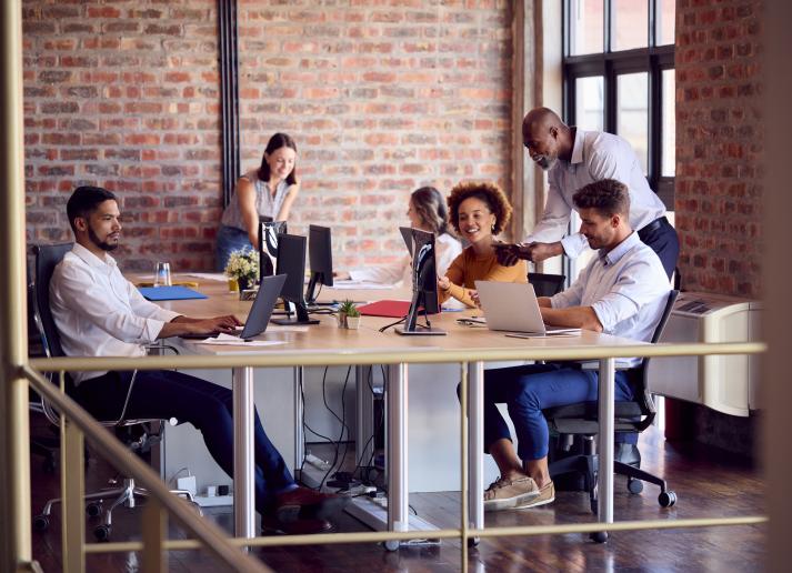 Colleagues talking around a desk in an open office space