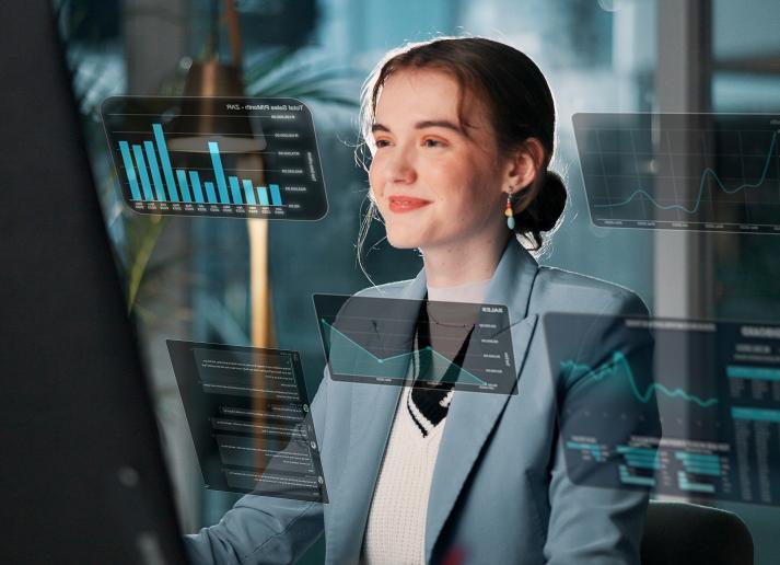 A young woman smiles as she sits at a computer
