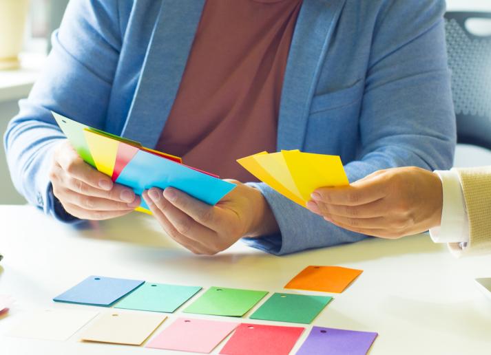 Two professionals consult their notes while sorting colorful index cards into groups