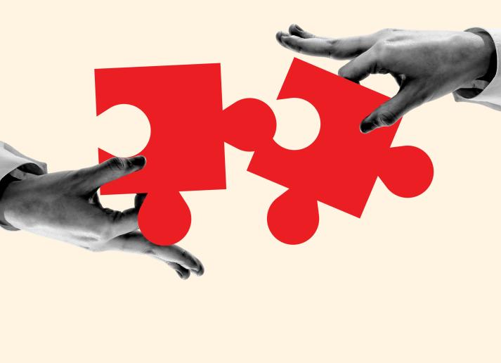 Hands connecting red puzzle pieces on a tan background