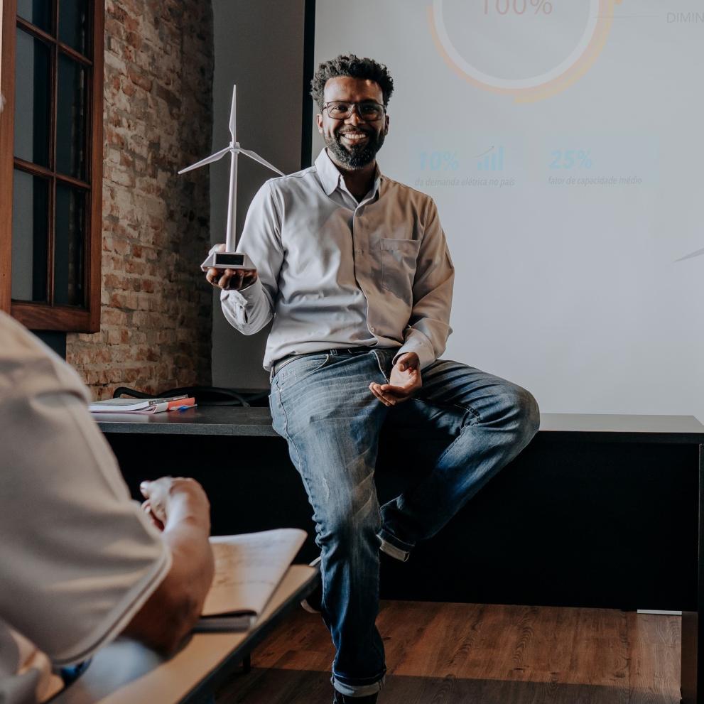 Man teaching two older people in a classroom, windmill in hand