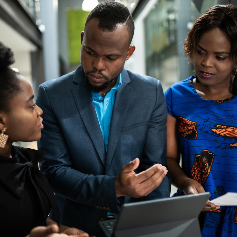 Three people standing looking at a computer