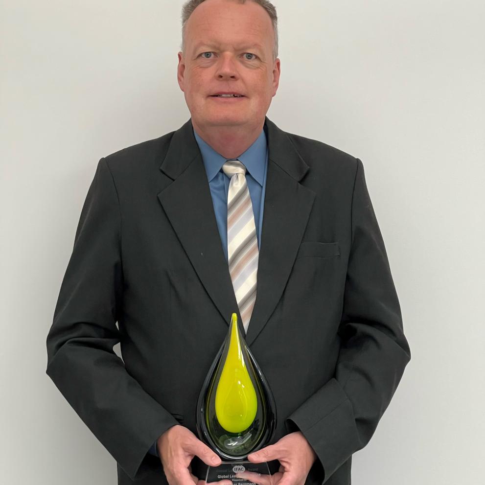 Man smiling and holding a plaque