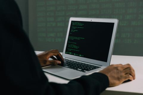 Man with computer that has green text