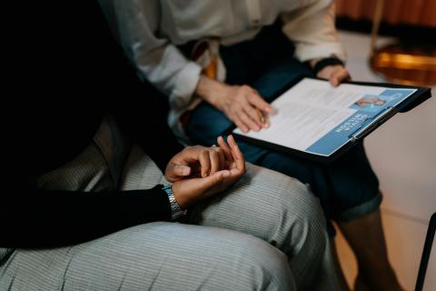Two people sitting, looking over a digital resume displayed on a tablet