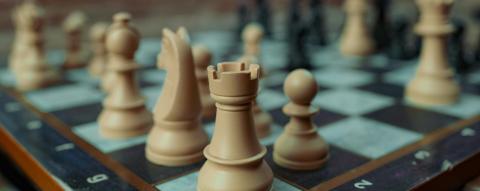 The view of a chess board from the corner, with tan and brown pieces set up