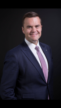 Portrait of a man standing and wearing a suit with a pink tie
