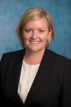 A woman wearing a black blazer smiles at the camera